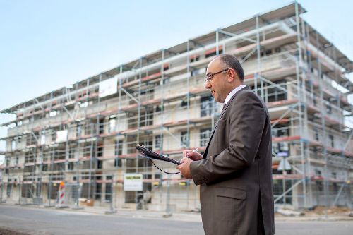 Immobiliengutachter Abdullah Ayhan mit Klemmbrett neben Immobilie