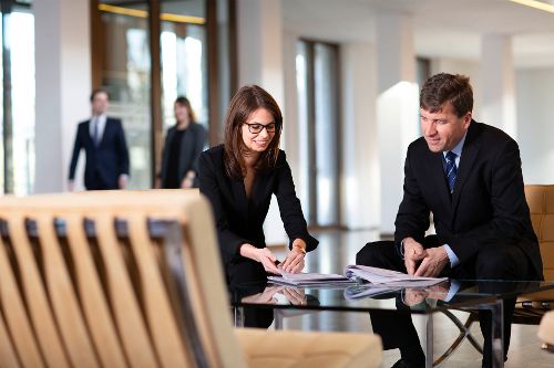 Mitarbeitende gehen Dokumente in der Lobby durch.