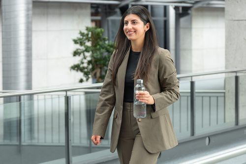 Eine junge Frau geht gut gelaunt einen hellen Gang entlang.