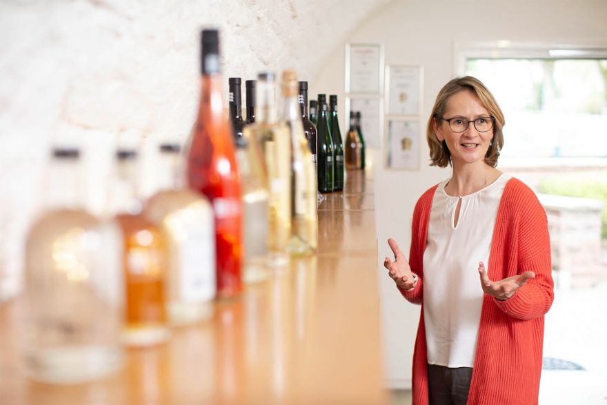 Jana Menzel vom Marketing und Vertrieb neben Weinflaschen
