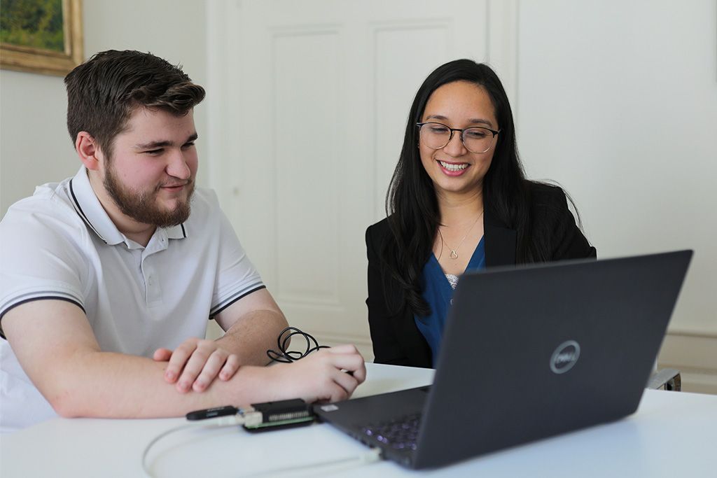 Zwei Personen arbeiten gemeinsam an einem Laptop.