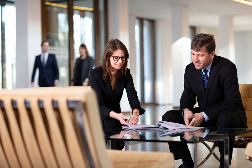 Mitarbeitende gehen Dokumente in der Lobby durch.
