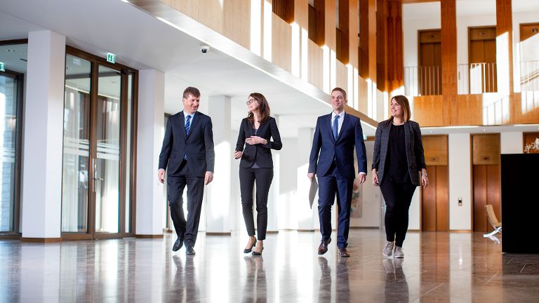 Mitarbeitende laufen durch die Lobby.