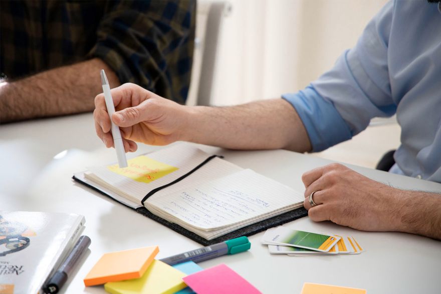 Person benutzt Notizbuch und Post-Its.