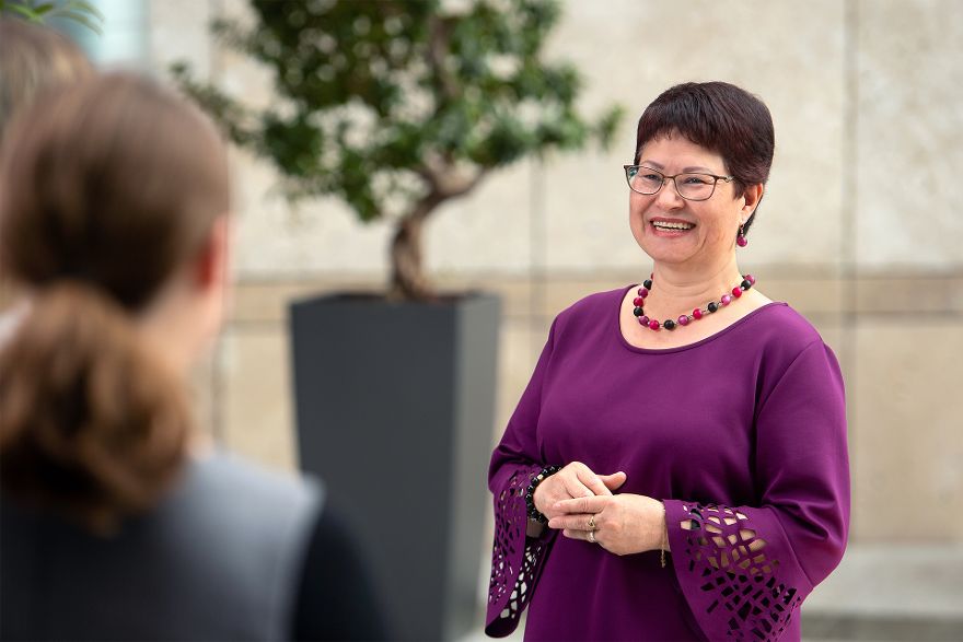 Frau Löffler im Gespräch mit einer Reporterin. Sie trägt ein lilanes Oberteil. Im Hintergrund steht ein kleiner Baum.