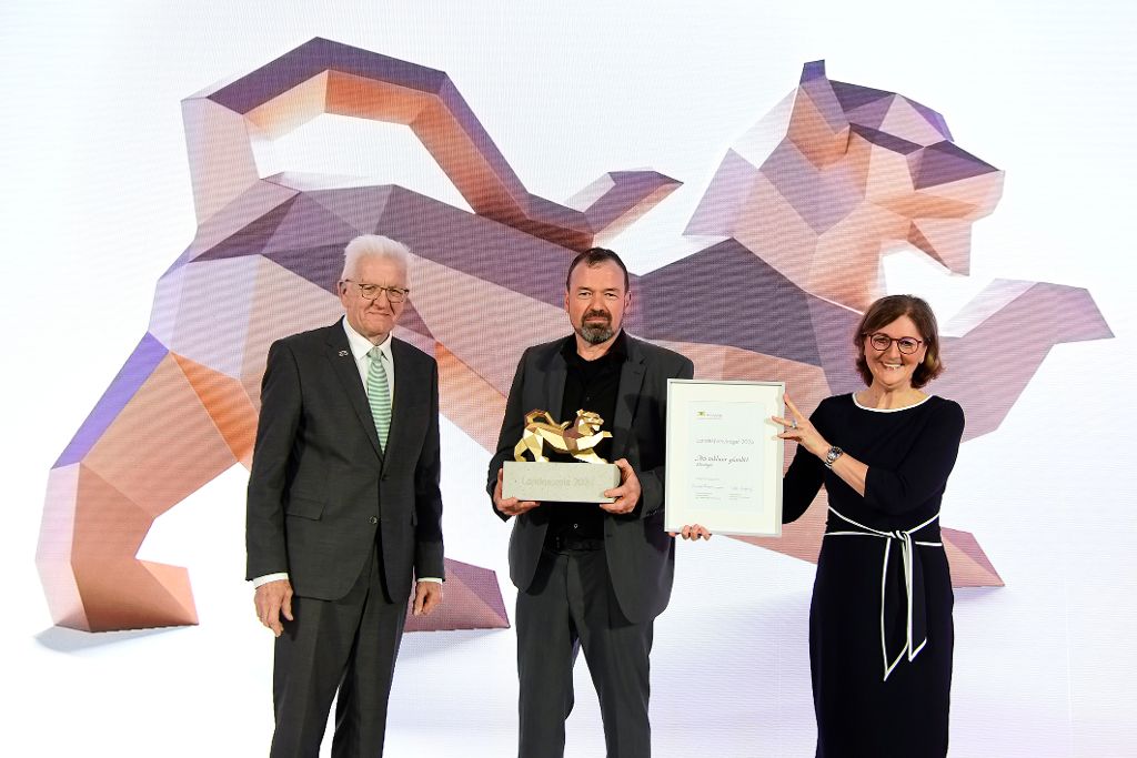 Ministerpräsident Winfried Kretschmann und Vorstandsvorsitzende der L-Bank Edith Weymayr überreichen Trophäe an AiS inklusiv.