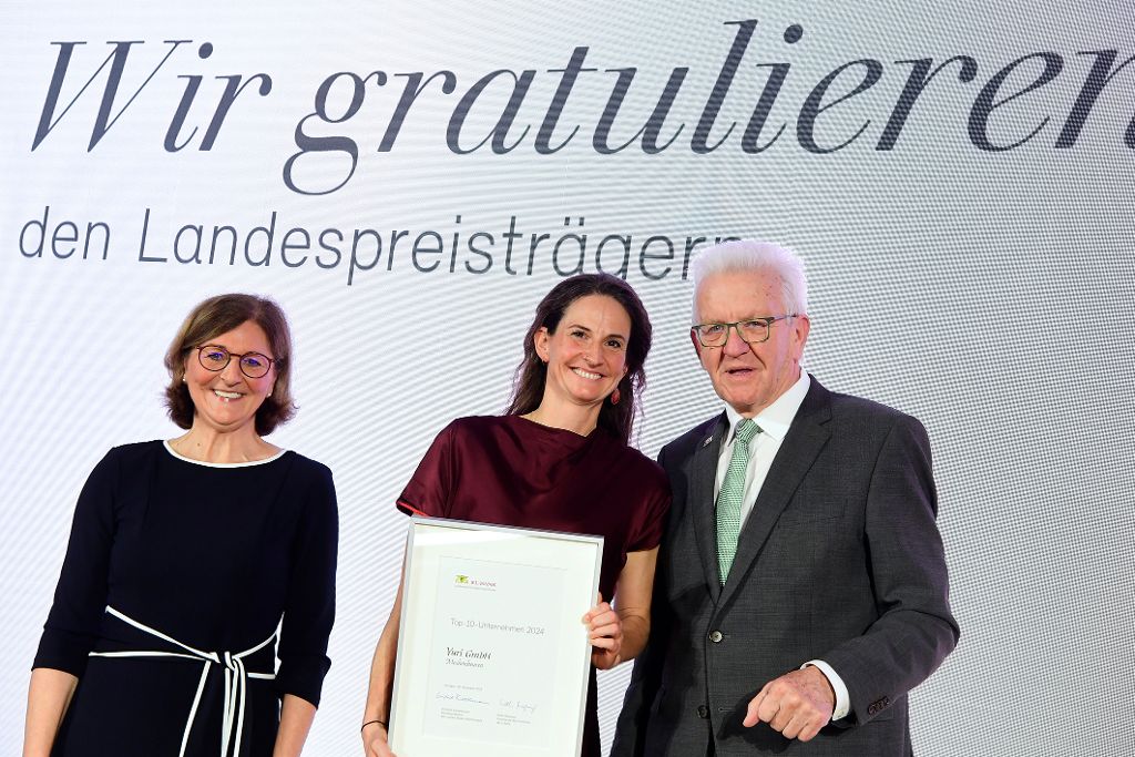 Ministerpräsident Winfried Kretschmann und Vorstandsvorsitzende der L-Bank Edith Weymayr überreichen Urkunde an Yuri.
