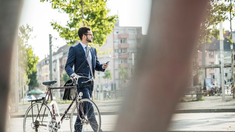 Ein Mann, der durch ein Wohngebiet läuft und ein Fahrrad neben sich her schiebt